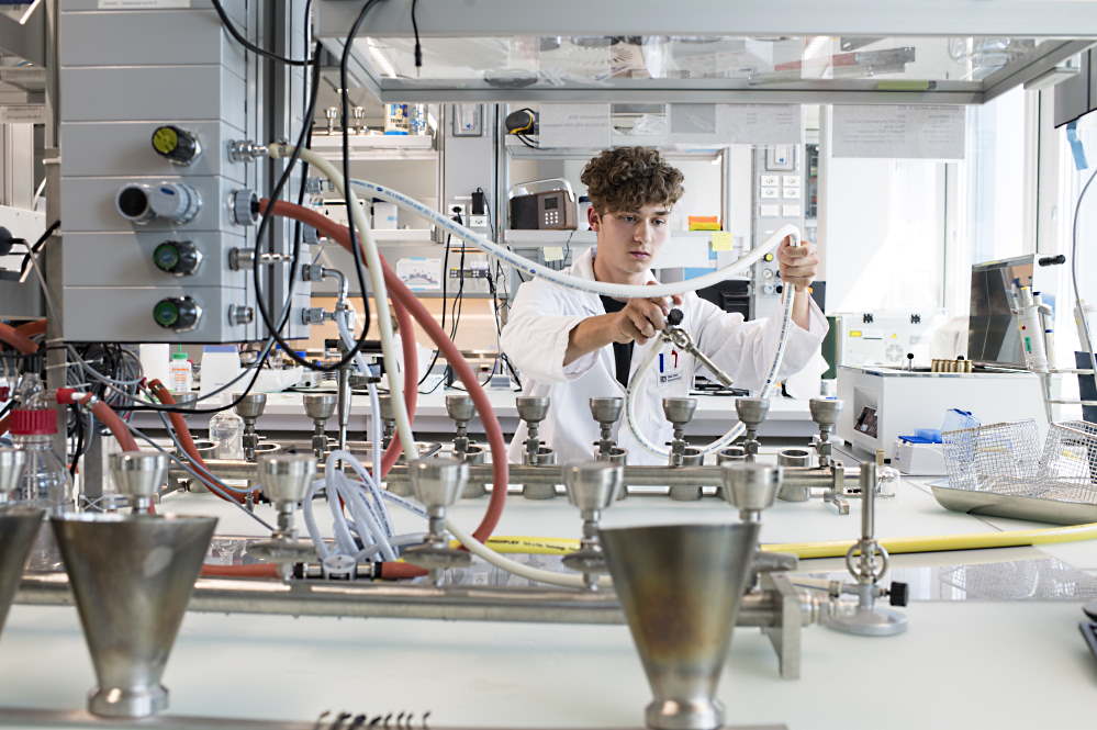 Ein junger Mann führt in einem Labor einen Versuch durch.