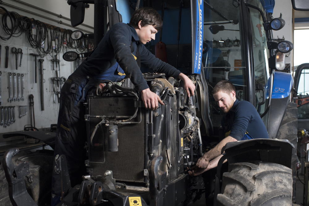 Zwei junge Techniker reparieren den Motor eines Traktors.
