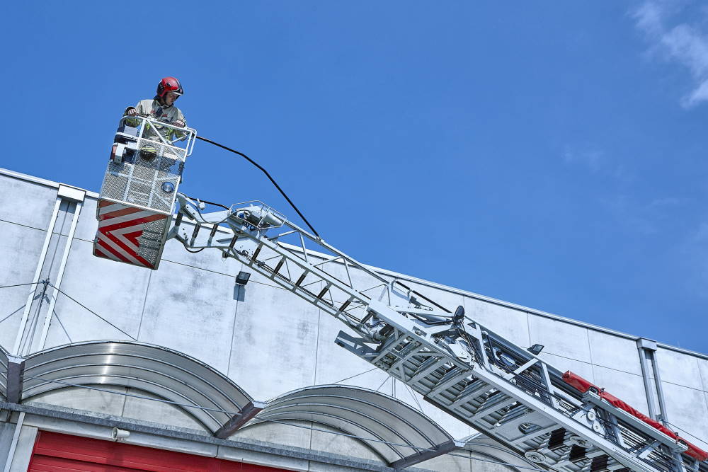 Ein Feuerwehrmann befindet sich hoch oben auf einem Glenkhebearm.