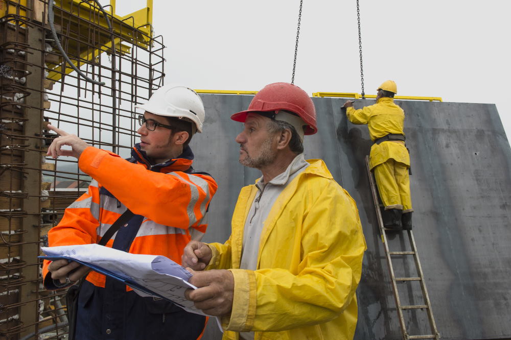 Zwei Männer auf der Baustelle besprechen die auszuführenden Arbeiten.