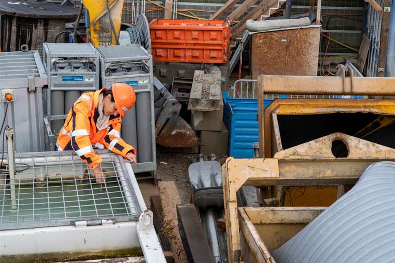 Eine Frau in Warnschutzbekleidung arbeitet auf einer Baustelle.