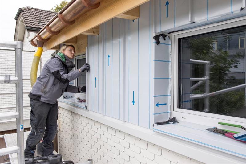 Eine Spenglerin arbeitet an der Verkleidung einer Aussenwand.