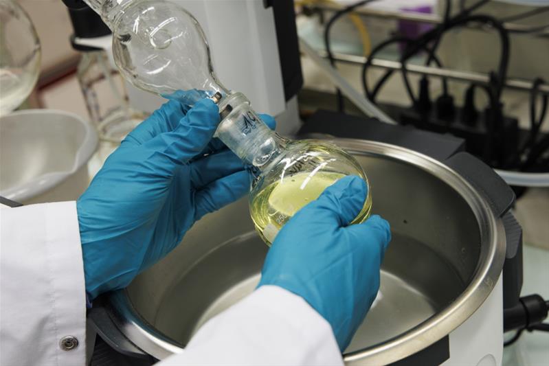 Eine Person hantiert in einem Labor mit einer Flüssigkeit.