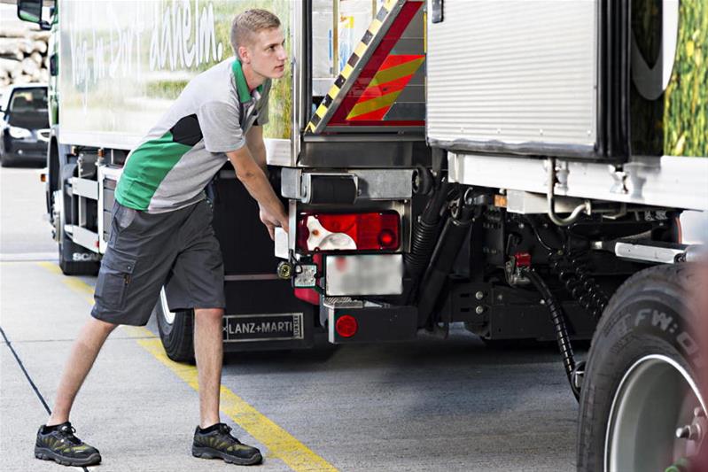 Ein junger Mann überprüft die Anhängerkupplung des Lastwagens.