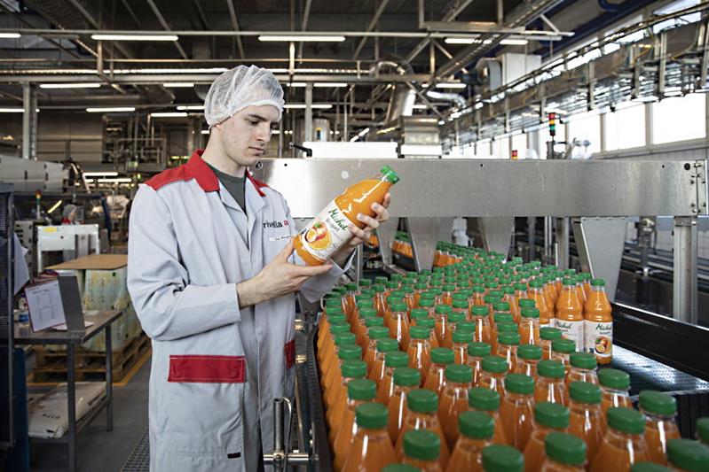 Ein Mann kontrolliert eine Flasche aus der Abfüllanlage von Fruchtsäften.