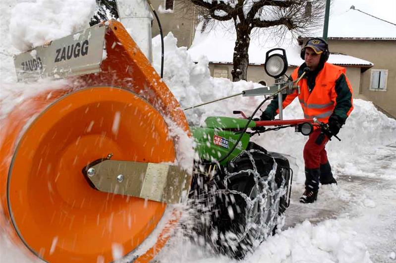 Ein Lernender räumt Schnee weg mit einer Maschine.