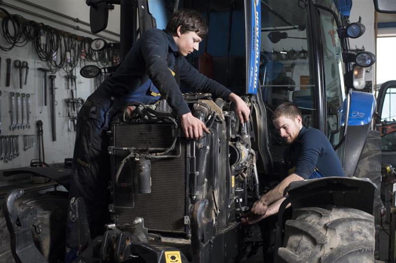 Zwei junge Techniker reparieren den Motor eines Traktors.