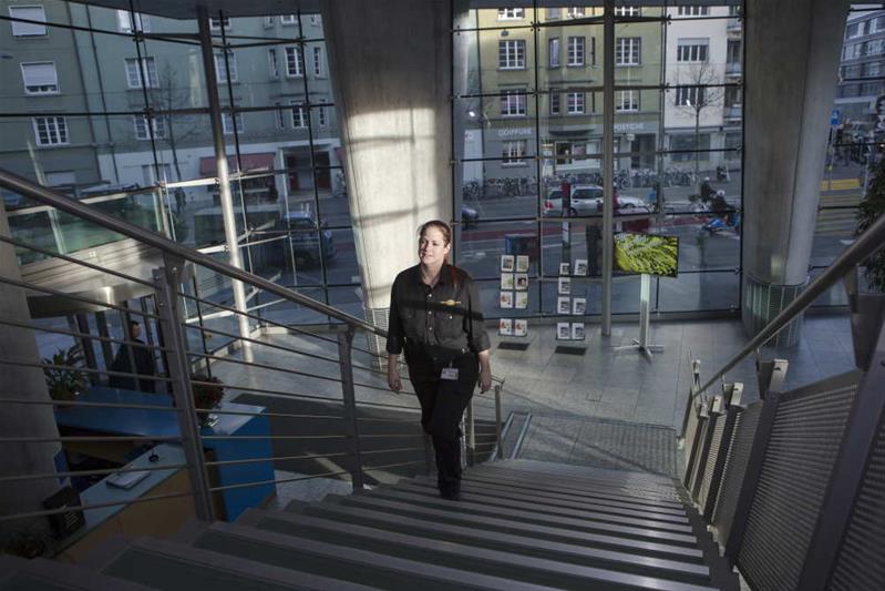 Eine Sicherheitsfachfrau steigt die Treppe in einem modernen Glasgebäude hoch.