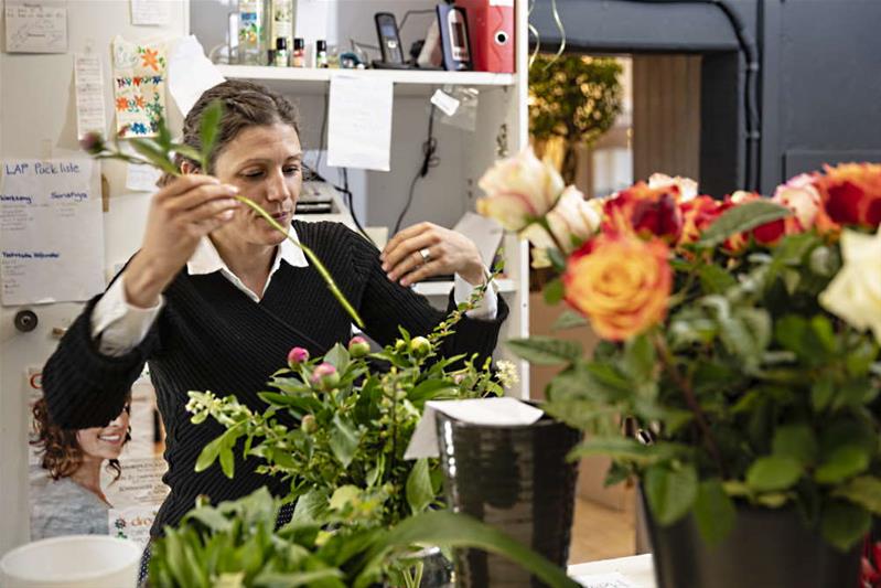 Eine Frau arrangiert einen Blumenstrauss in einem Blumengeschäft.