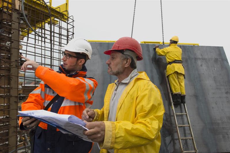 Zwei Männer auf der Baustelle besprechen die auszuführenden Arbeiten.