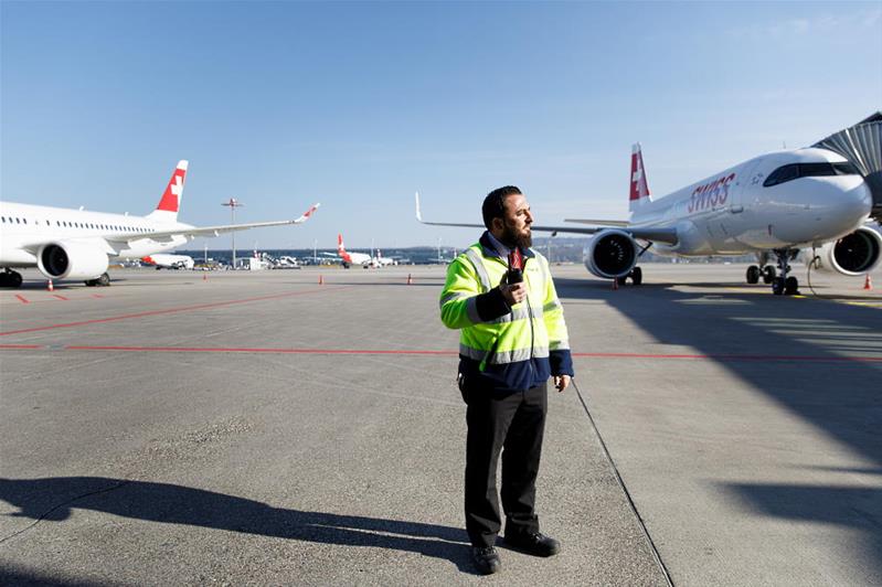 Ein Mann in Warnkleidung weist die Flugzeuge auf dem Flugplatz ein.