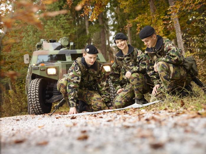Drei Angehörige der Schweizer Armee studieren einen Plan.