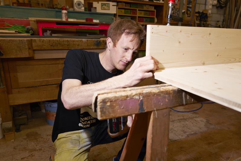 Dominik Lehmann Flury baut Bühnenelemente aus Holz zusammen.