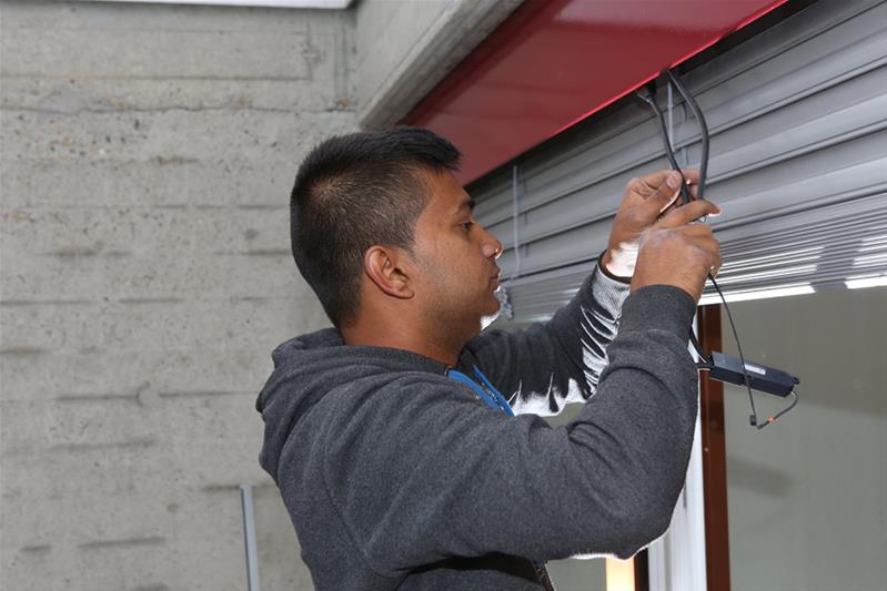 Ein Lernender befestigt ein Kabel für eine elektrische Store.