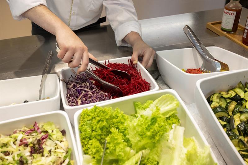 Ein Lernender bereitet das Salatbuffet vor.