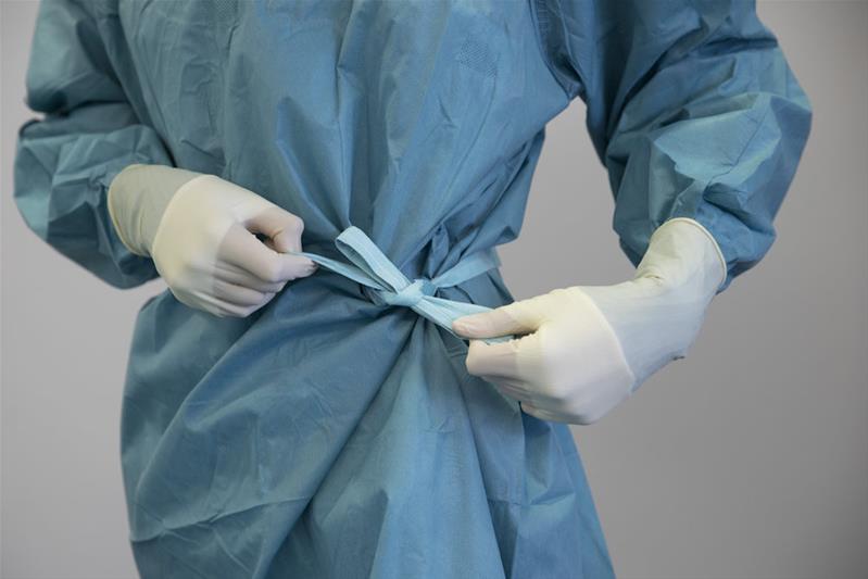 Ein Arzt bindet seinen Arztkittel